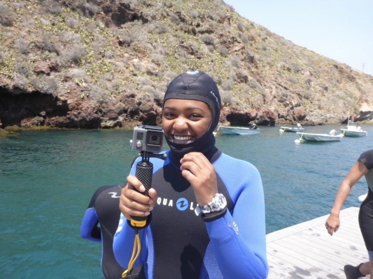 Aliyah Griffith in a wetsuit holding a gopro